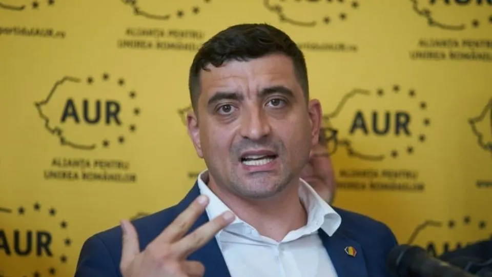 Un bărbat cu părul scurt și sacou albastru vorbește în fața unui fundal galben cu logoul AUR.