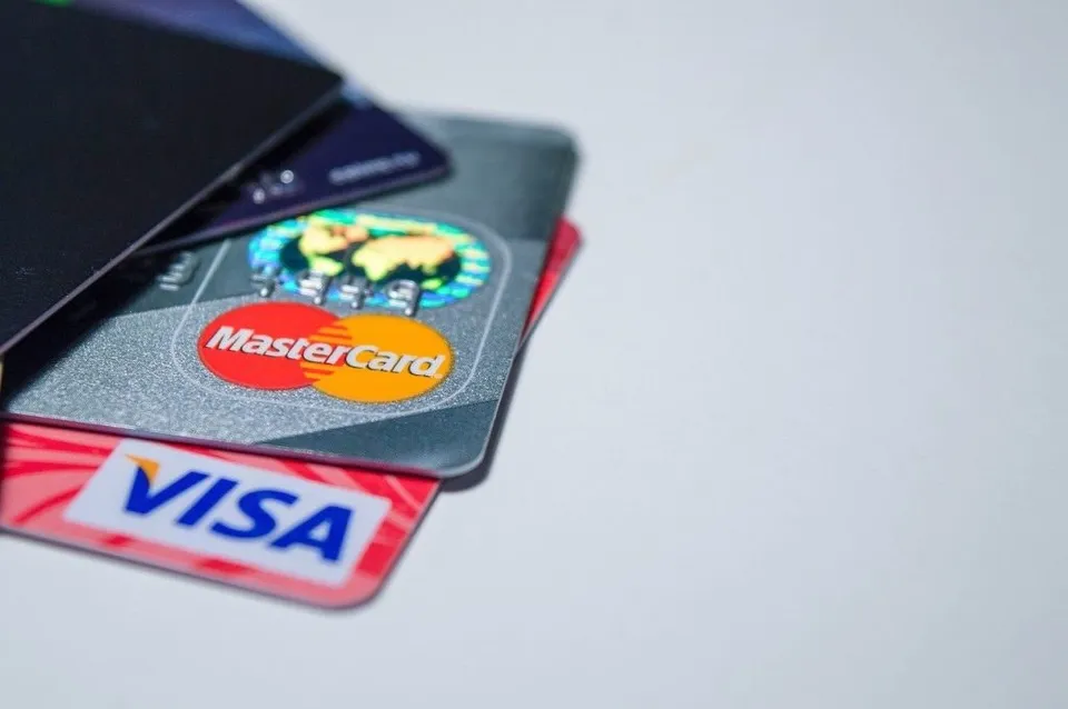 Mai multe carduri de plată, inclusiv unul cu logo-ul Mastercard și unul cu logo-ul Visa, sunt așezate suprapus pe o suprafață albă.