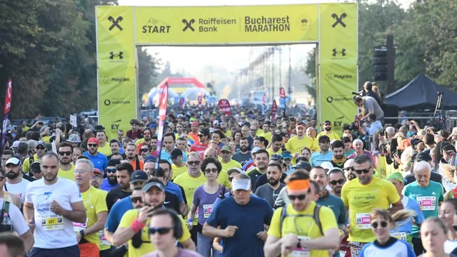 O mulțime de oameni în haine sportive colorate aleargă pe o stradă sub o poartă galbenă marcată cu textul START și Bucharest Marathon.