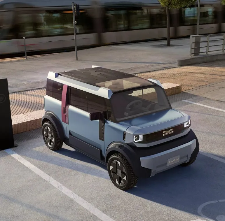 Un vehicul compact de culoare albastru deschis cu acoperiș negru este parcat pe un drum asfaltat lângă o zonă cu trotuar din lemn.