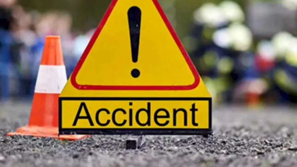 Un semn de avertizare triunghiular galben cu un punct exclamativ și cuvântul Accident este plasat pe asfalt lângă un con de circulație portocaliu.