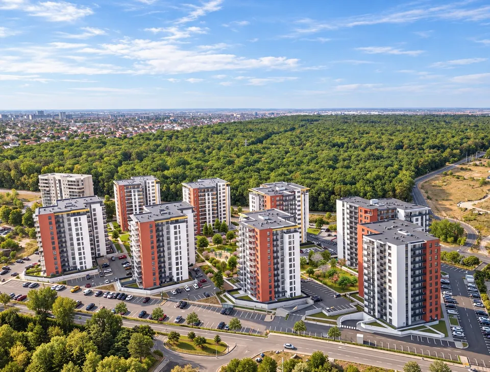 Mai multe clădiri de apartamente înalte, cu fațade albe și portocalii, sunt dispuse pe o suprafață verde lângă o pădure densă sub un cer senin.