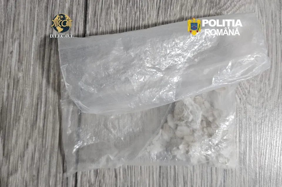 Două pungi mici de plastic transparent conținând o substanță albă granulară sunt așezate pe o suprafață de lemn cu textură gri.