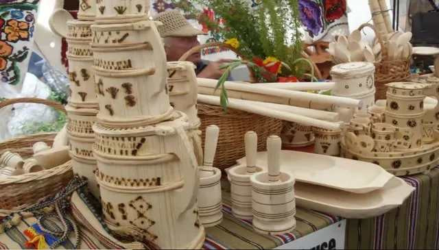 Diverse obiecte din lemn sculptat și coșuri de răchită sunt expuse pe un stand de vânzare.