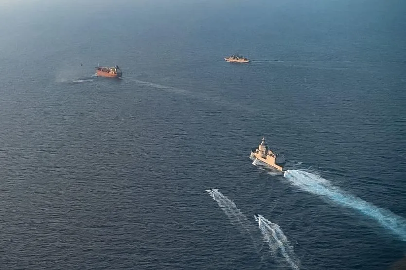 Trei nave navighează pe apă, lăsând urme albe în spate.
