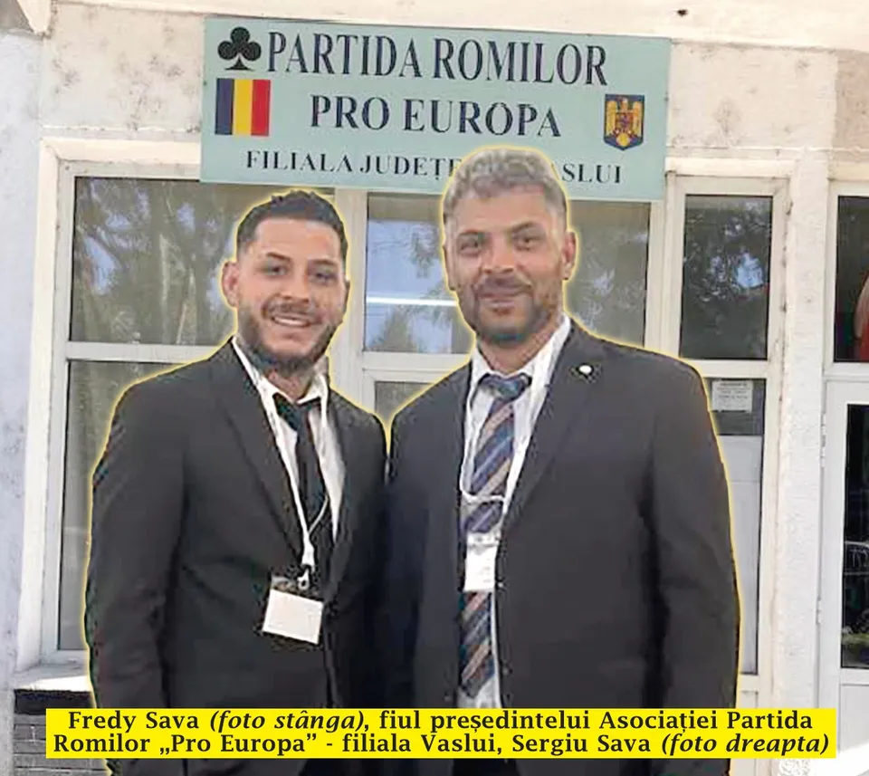 Un bărbat cu părul scurt și costum negru stă lângă un bărbat cu barbă, costum negru și cravată în culorile alb, albastru și gri.