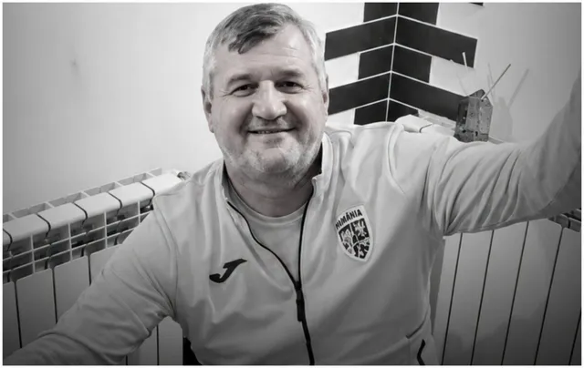 Un bărbat zâmbind poartă un hanorac alb cu un logo pe piept și un fermoar în față.