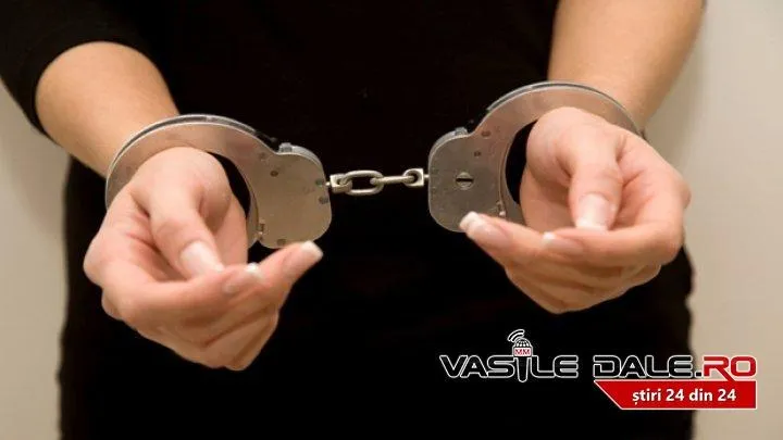 O persoană în haine negre ține o pereche de cătușe metalice cu ambele mâini.