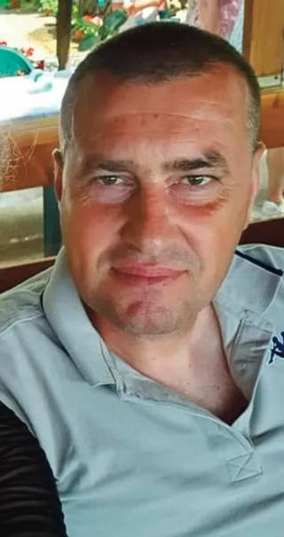Un bărbat cu păr scurt și cămașă polo gri este surprins într-o fotografie de tip selfie.