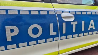 Un detaliu al portierei unei mașini de poliție care prezintă inscripția POLITIA pe un fundal albastru cu benzi galbene și albe.