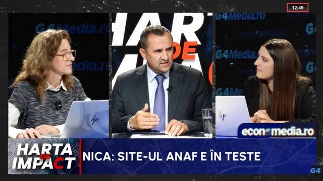 Trei persoane stau la o masă într-un studio, un bărbat în costum și cravată fiind poziționat între două femei cu laptopuri deschise în față.