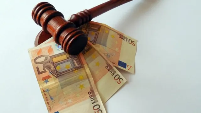 Un ciocan de lemn de judecată este așezat peste câteva bancnote de cincizeci de euro pe un fundal alb.