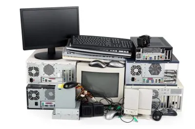 Un monitor negru, tastaturi, mouse-uri și diverse unități de calcul și componente electronice sunt grupate pe un fundal alb.