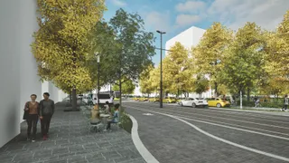 O stradă cu trotuar pavat, arbori cu frunze galbene, mașini parcate și persoane așezate la o masă de exterior sub cerul înnorat.