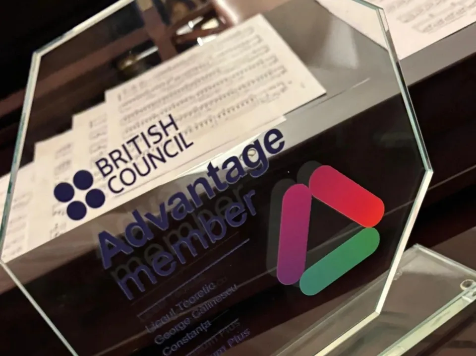 Un trofeu din sticlă transparentă prezintă logoul British Council și textul Advantage member pe un fundal cu partituri muzicale.