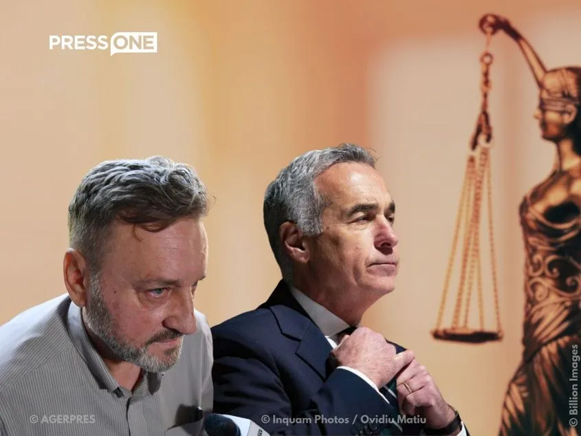 Un bărbat cu părul scurt și barbă gri privește în jos, în timp ce un alt bărbat într-un costum închis privește spre lateral lângă o statuie a justiției.