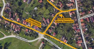 O hartă aeriană prezintă străzi evidențiate cu linii galben-portocalii și etichete text pe fundalul unui cartier cu case și vegetație.