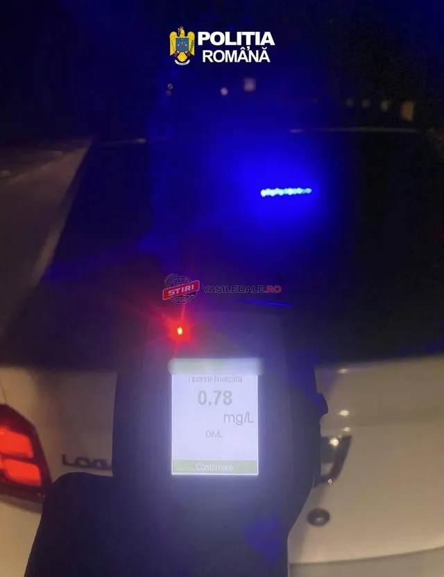 O mână ține un aparat de etilotest care afișează valoarea 0,78 mg/L pe un ecran luminos, în fața unei mașini albe noaptea.