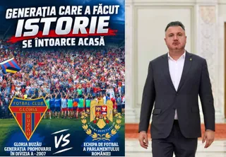 Un bărbat într-un costum închis la culoare și cămașă albă stă în fața unui fundal alb, lângă un afiș care prezintă o mulțime de oameni pe un stadion.