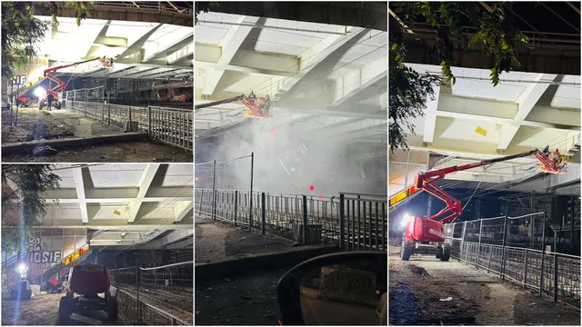 Un utilaj cu braț telescopic este poziționat lângă o structură metală sub o suprafață de beton iluminată puternic noaptea.