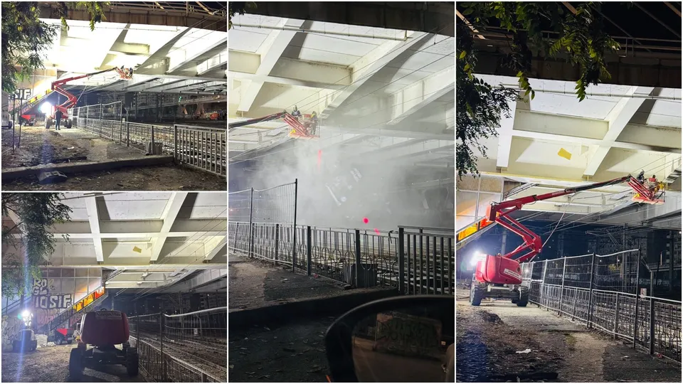 Un utilaj cu braț telescopic este poziționat lângă o structură metală sub o suprafață de beton iluminată puternic noaptea.