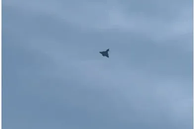 Un avion mic zboară pe un cer acoperit de nori gri.