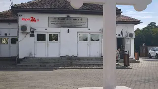 O clădire albă cu acoperiș de țiglă și un panou cu textul „CIMITIRUL NR. 8” este situată în spatele unui stâlp alb.