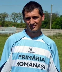 Un bărbat cu părul scurt poartă un tricou sportiv albastru și alb cu inscripția PRIMĂRIA ROMÂNAȘI.