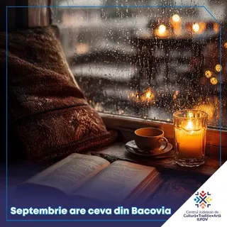 O carte deschisă, o cană pe farfurie și o lumânare aprinsă sunt așezate pe un pervaz lângă o fereastră cu picături de apă.
