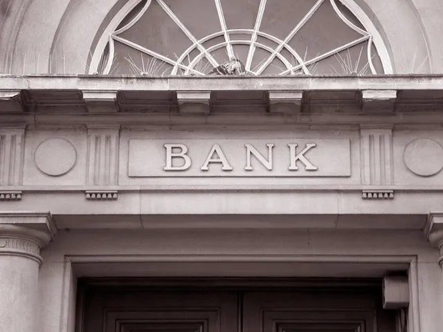 O fațadă de clădire cu inscripția BANK sculptată în piatră deasupra unei intrări cu coloane și un element decorativ circular deasupra.