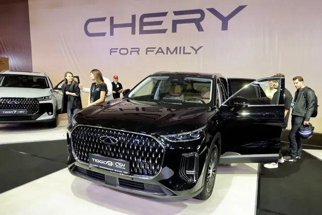 Un SUV negru cu portierele deschise este expus într-un spațiu de prezentare, în fața unui panou cu textul CHERY FOR FAMILY.