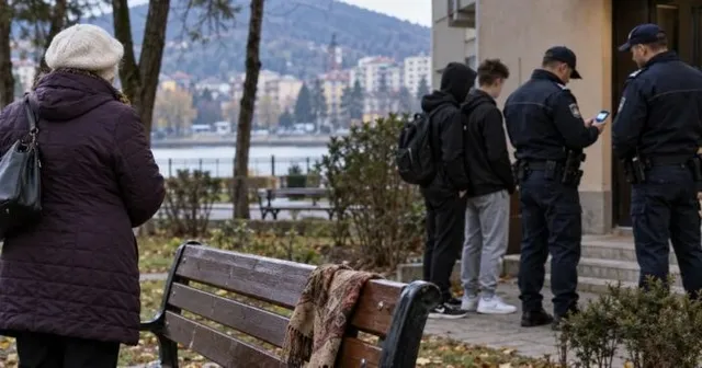 Trei bărbați în uniformă de polițist stau lângă doi tineri într-un parc, lângă un banc de lemn.