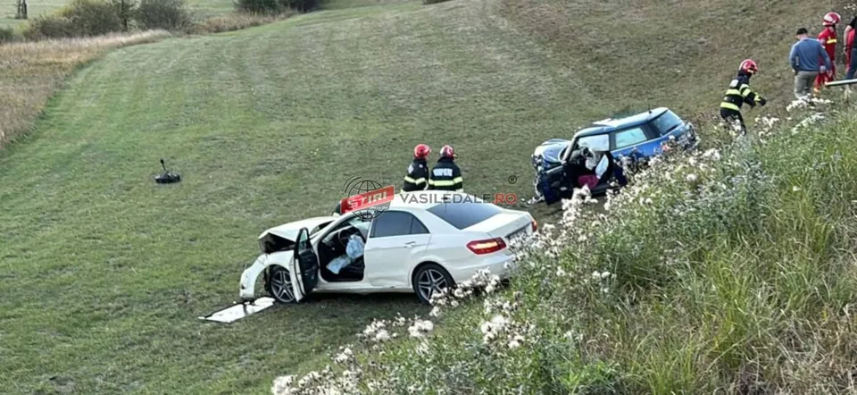 Două autoturisme sunt situate pe o panta de iarbă, în prezența unor persoane purtând echipamente de protecție colorate.
