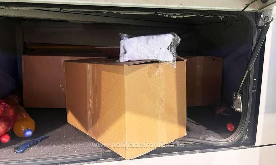 În interiorul unui compartiment, trei cutii de carton maro sunt așezate lângă obiecte colorate și un obiect lung și subțire.