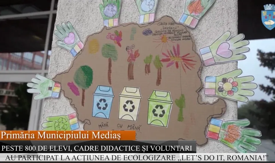 O lucrare artistică pe carton în formă de hartă prezintă desene cu copaci, flori, containere de reciclare și mâini colorate pe margini.