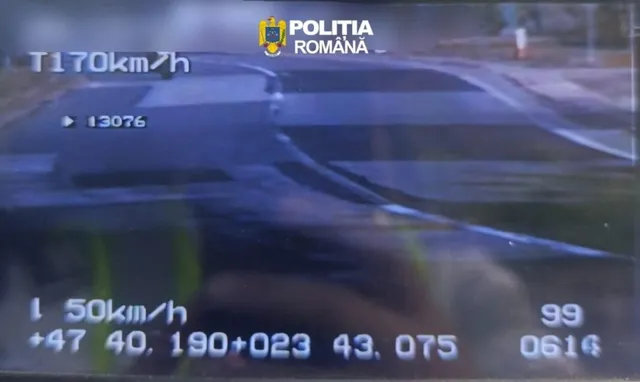 O imagine de pe un ecran afișează textul T170km/h, un număr de identificare și marcaje rutiere pe o suprafață asfaltată întunecată.