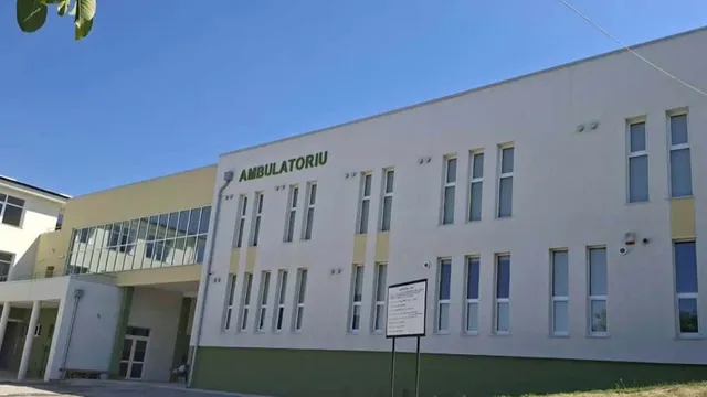 O clădire albă cu ferestre înalte și verticale prezintă inscripția AMBULATORIU deasupra ferestrelor de la etaj.
