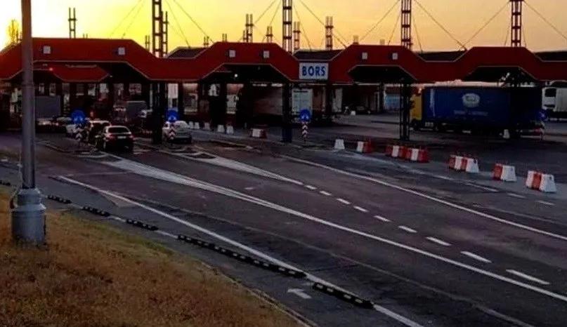 O imagine de la punctul de trecere a frontierei Borș prezintă mai multe puncte de control acoperite, vehicule și drumuri asfaltate sub un cer de apus.