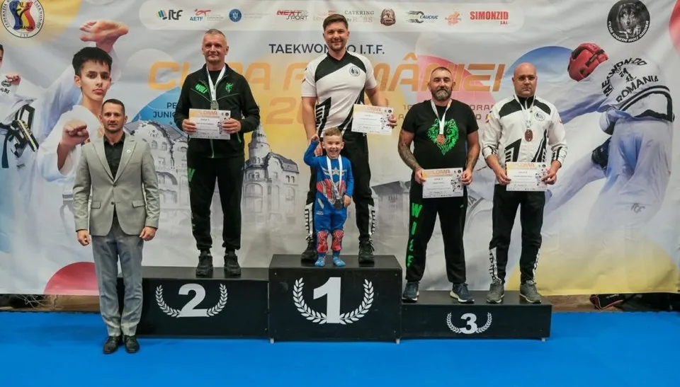 Cinci bărbați și un copil stau pe un podium de premiere în fața unui panou publicitar cu textul Cupa României.