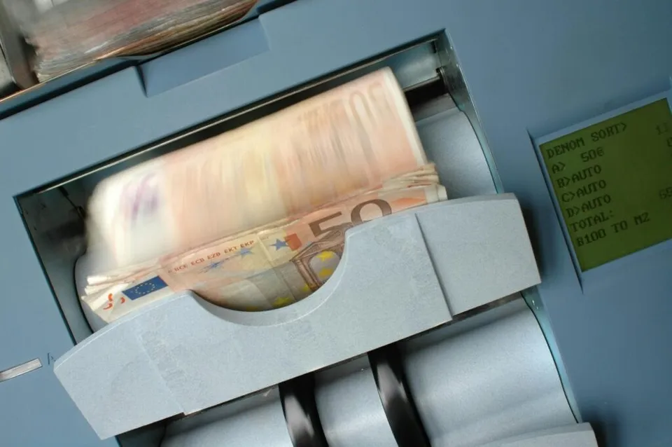 Banii de tip bancnote de cincizeci de euro sunt afișați într-o deschidere de un automat bancar.