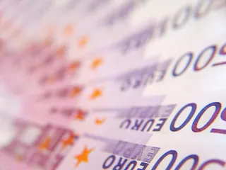 Imaginea prezintă un plan de detalii cu bancnote de euro, afișând cifrele cinci sute și cuvântul euro pe un fundal colorat.