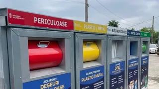 O serie de containere de colectare colorate, marcate cu text și simboluri, conținând obiecte de culoare roșie, galbenă și albastră în compartimente deschise.