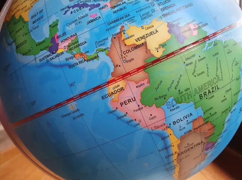 Un glob terestru arată harta continentului America de Sud pe un fundal albastru.