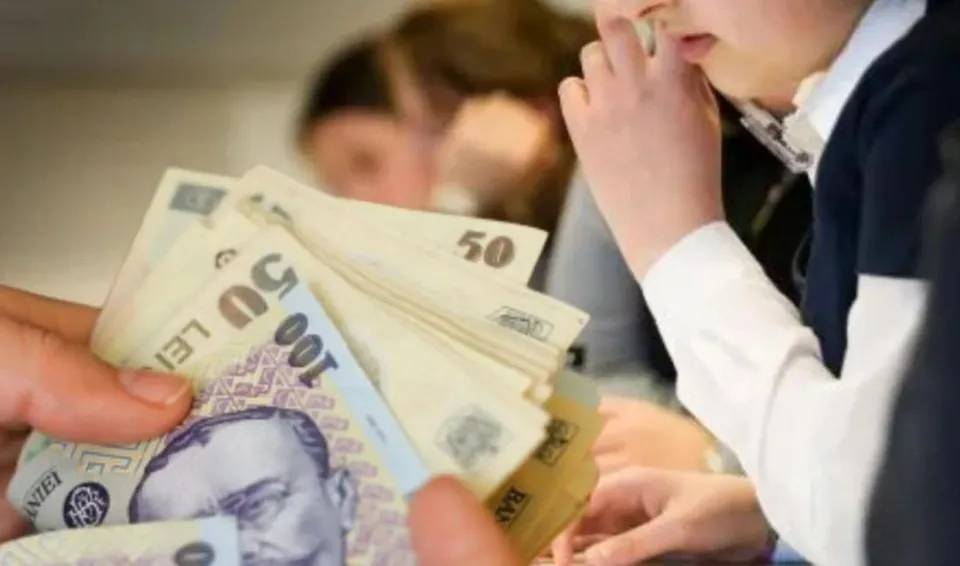 O persoană ține mai multe bancnote de 50 și 100 de lei în mână, în timp ce un copil stă în apropiere.