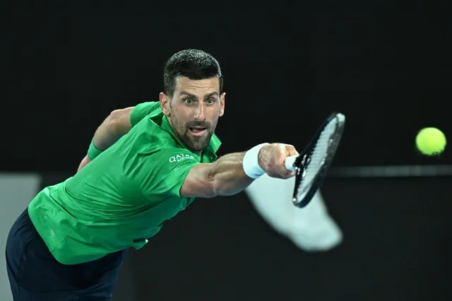 Un bărbat cu tricou verde și pantaloni închiși lovește o minge de tenis cu o rachetă într-o poziție de întindere.