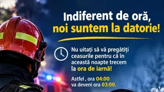 A firefighter in a red helmet and dark uniform is shown from behind, looking towards a blurred background with emergency lights and text about daylight saving time.