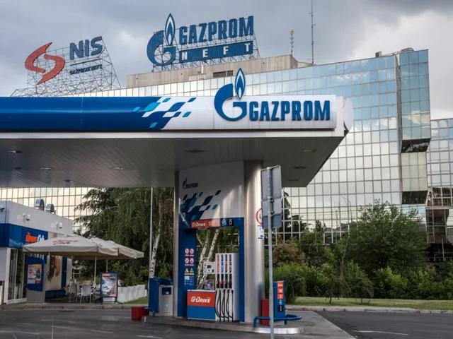 O stație de alimentare Gazprom cu panouri de afișaj și pompe de benzină este situată în fața unui clădire cu fațadă de sticlă.