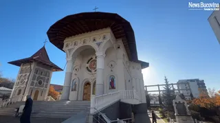 O clădire de biserică albă cu acoperiș în formă de cupolă și un turn separat cu acoperiș în pante sunt situate sub un cer senin.
