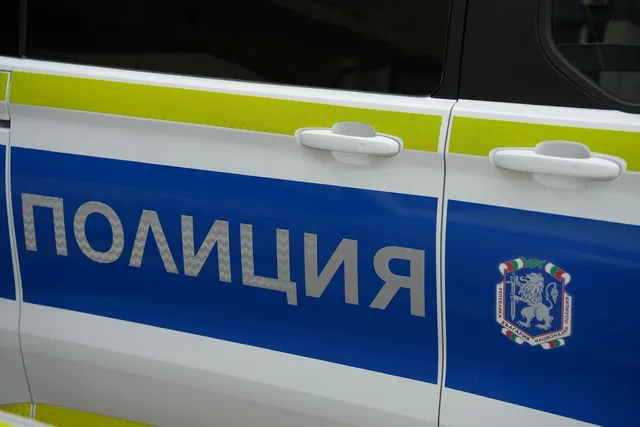 Un autovehicul alb cu o bandă albastră pe care scrie textul scris în alfabet chirilic și un emblema colorată.