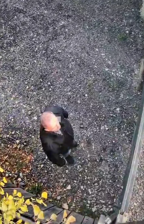 O persoană îmbrăcată în negru stă așezată pe un teren acoperit cu pietriș fin.